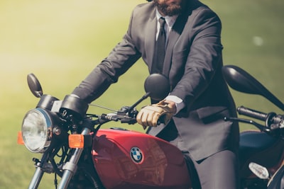 person wearing gray suit jacket riding bmw motorcycle distinguished teams background