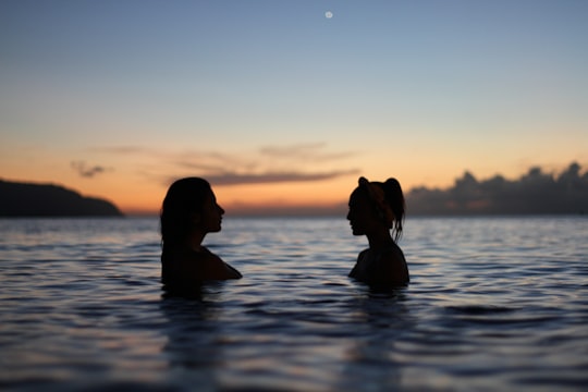 silhouette of two woman face to face in body water in Haleiwa United States