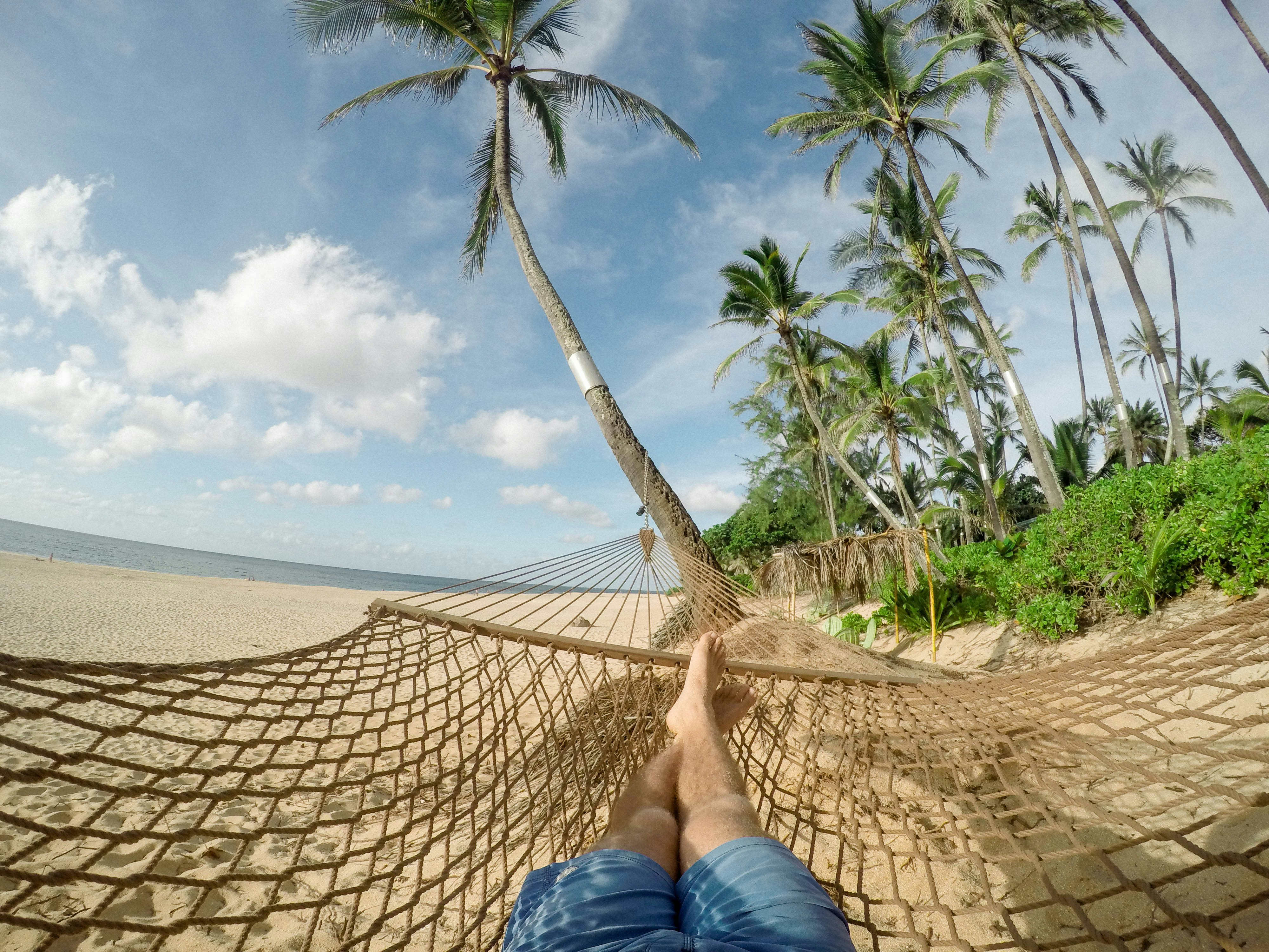 A person lying down in a hammock on the beach.