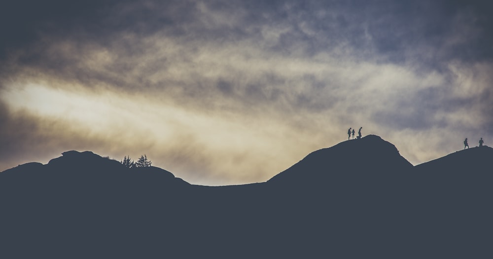 silhouette of people crossing a mountain