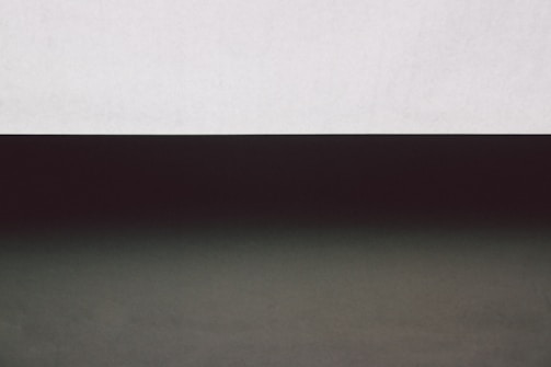 A minimalist composition with a stark contrast between two horizontal sections. The upper part is a light gray band, while the lower section is dark, creating a gradient effect.