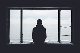 Lonely man looking out through window