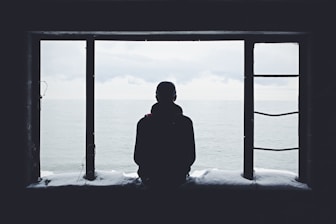 Lonely man looking out through window