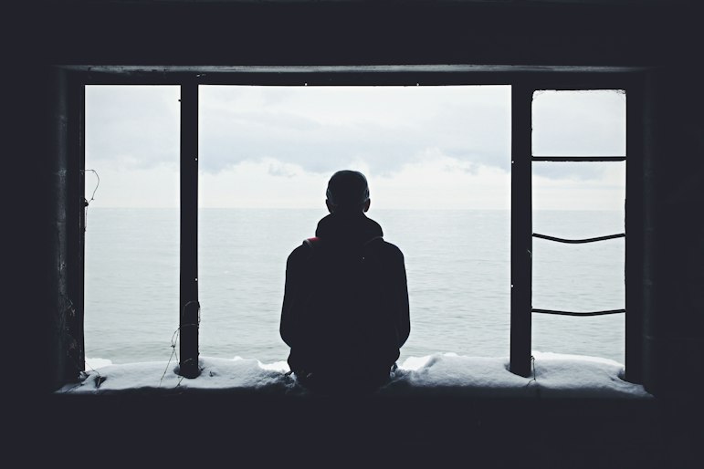 A person sitting alone, gazing out at the sea