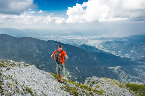 flow man standing on peak front of mountain at daytime