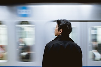 close-up photography of man standing front of train