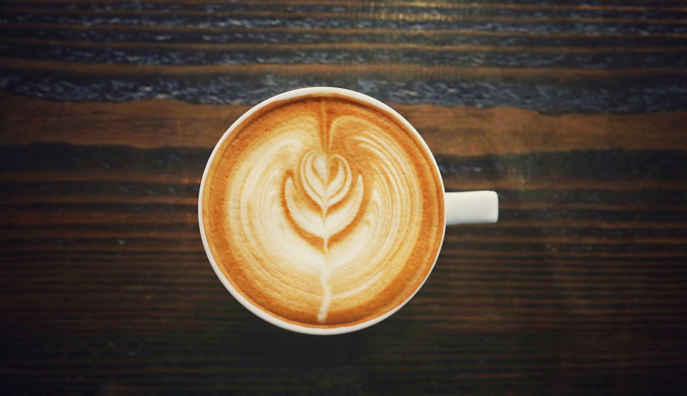 cup of cappuccino on brown surface