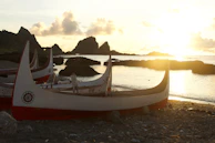 Sunset casting warm golden hues over traditional fishing boats resting in calm Andaman waters.
