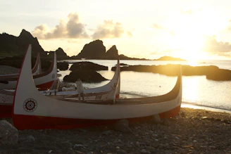 Sunset casting warm golden hues over traditional fishing boats resting in calm Andaman waters.