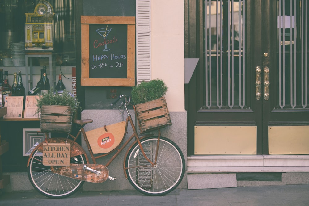 Bicicleta de la ciudad marrón cerca de la puerta de madera marrón