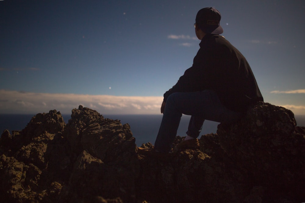 personne assise sur le rocher regardant le ciel