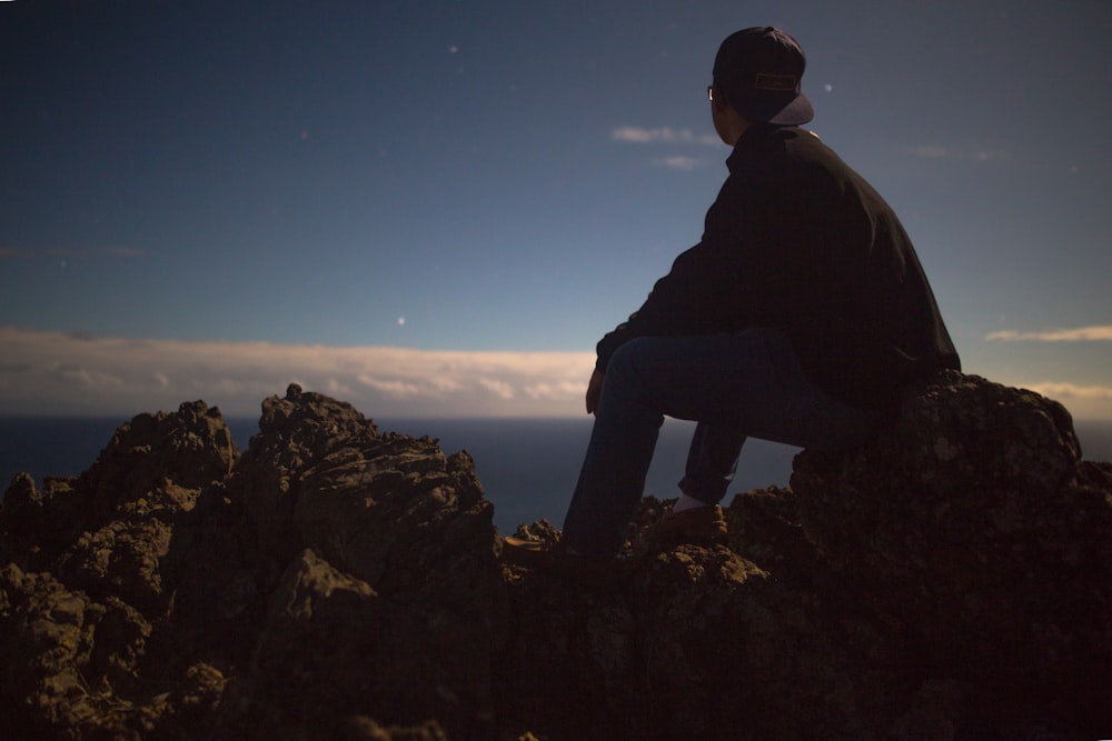 Persona seduta sulla roccia che guarda il cielo