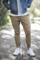 man wearing brown fitted jeans and sneakers standing on road at daytime