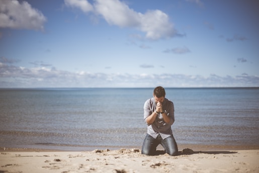 man kneeling down near shore