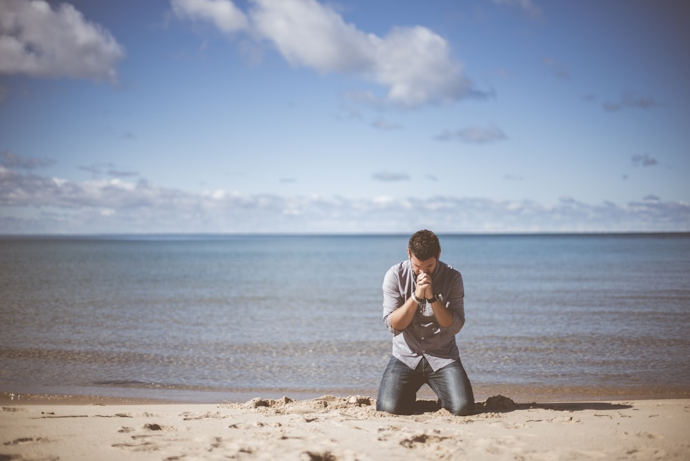 homme agenouillé près du rivage