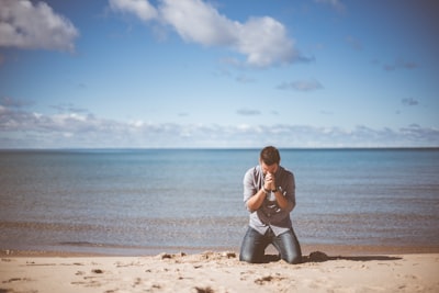 man kneeling down near shore thankful teams background