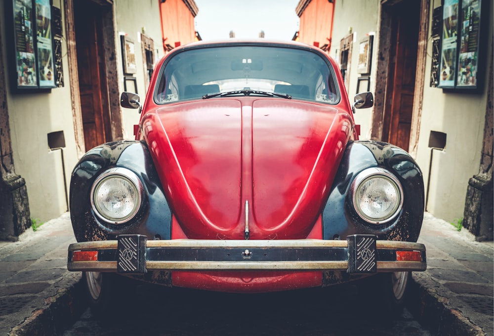 photo of red and black Volkswagen Beetle in alley