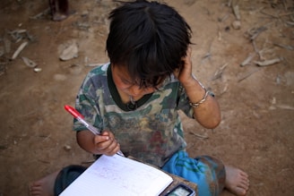 A peaceful scene showing a child memorizing Quranic verses with a notebook and pen.