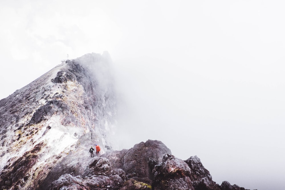 Dos personas de pie en la montaña ligeramente cubiertas de niebla durante el día