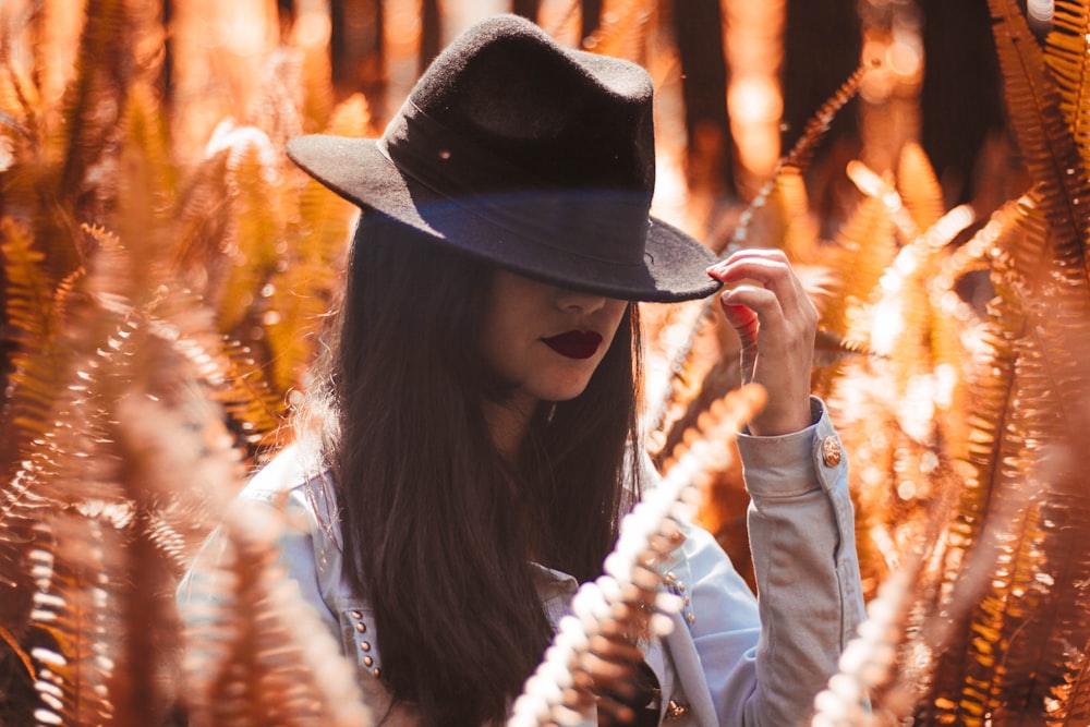 photography of woman in white long-sleeved top holding black bucket hat