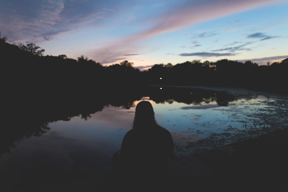 silhouette of person sitting near body of water