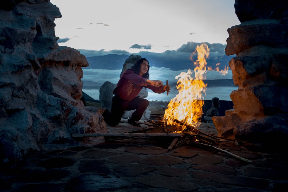 person kneeling in front of bonfire outside