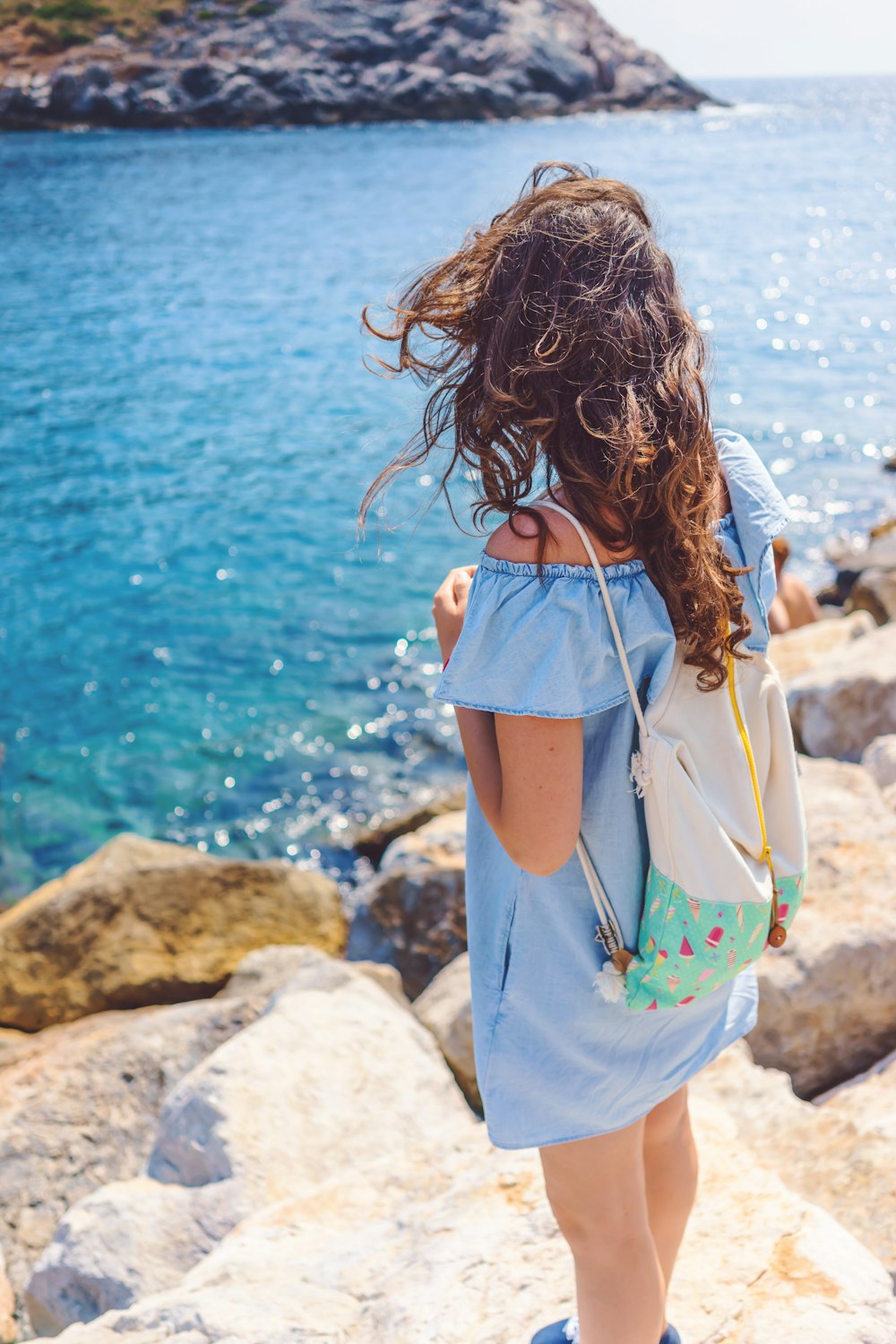 woman standing on brown rock near body of water