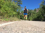 An outdoor trail with a runner mid-stride surrounded by lush greenery.