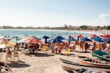 A vibrant beach scene with colorful umbrellas and a foldable beach wagon loaded with coolers and towels.