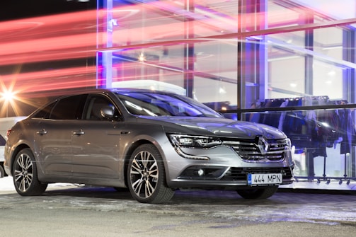 A sleek metallic grey car parked outside the cs-mobil dealership in Bavaria under a bold red sky at dusk.