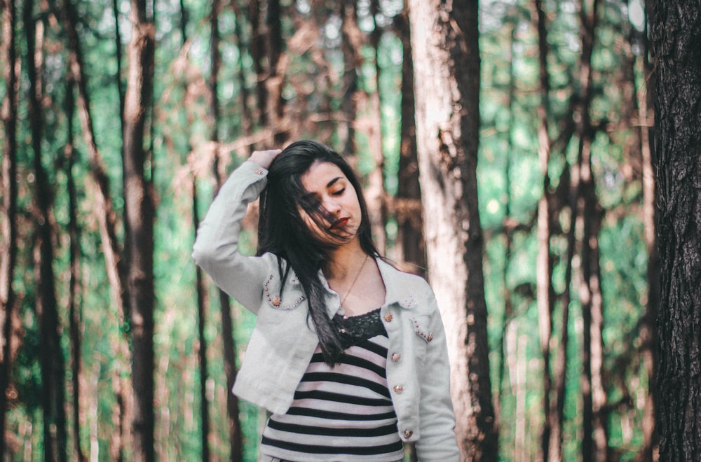 A young woman brushing back her hair in a forest