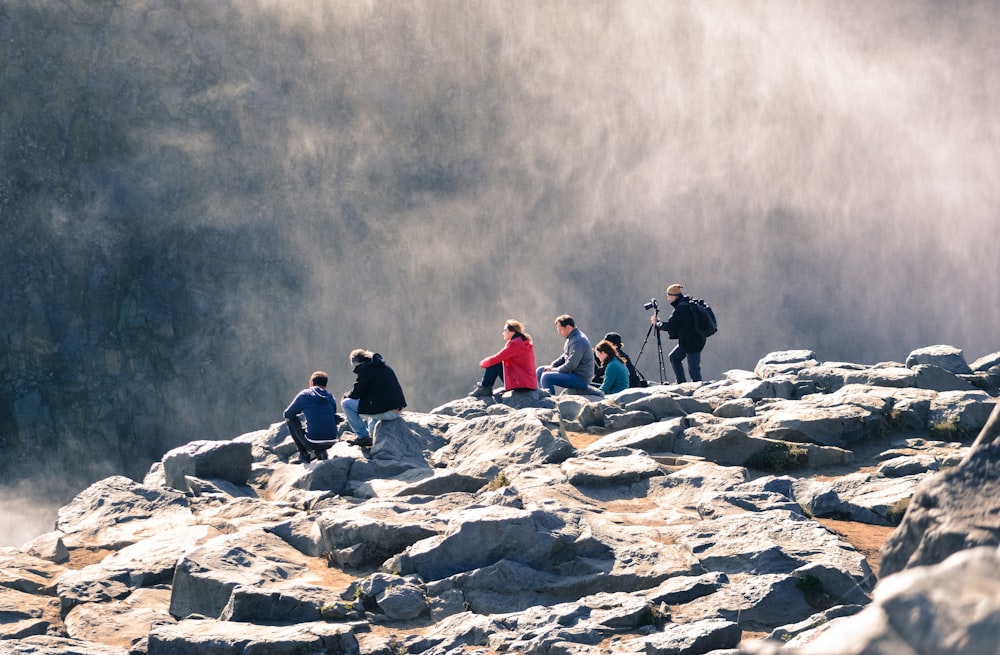 gruppo di persone che si siedono sulla roccia grigia