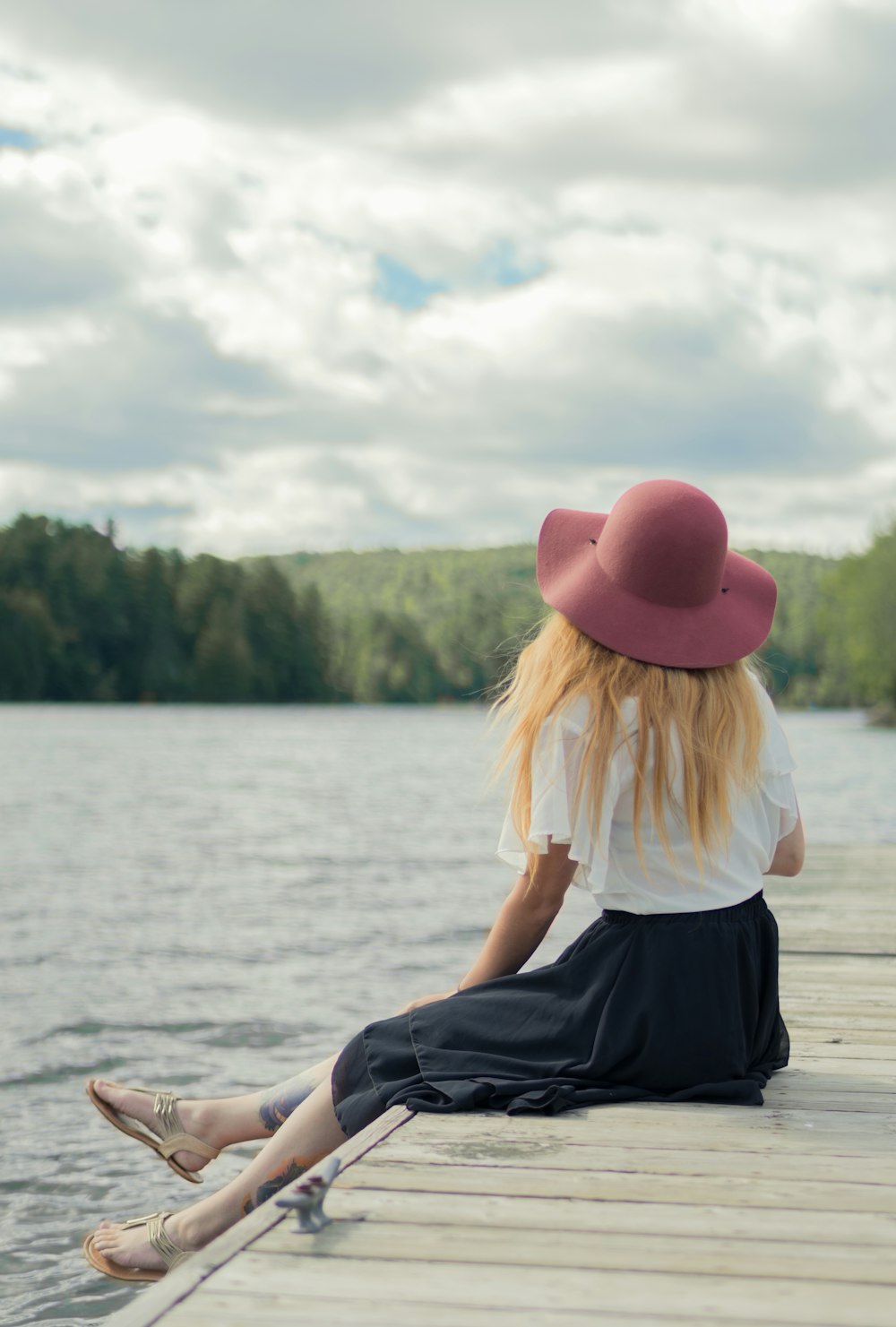 woman sitting on dock under cumulus clouds