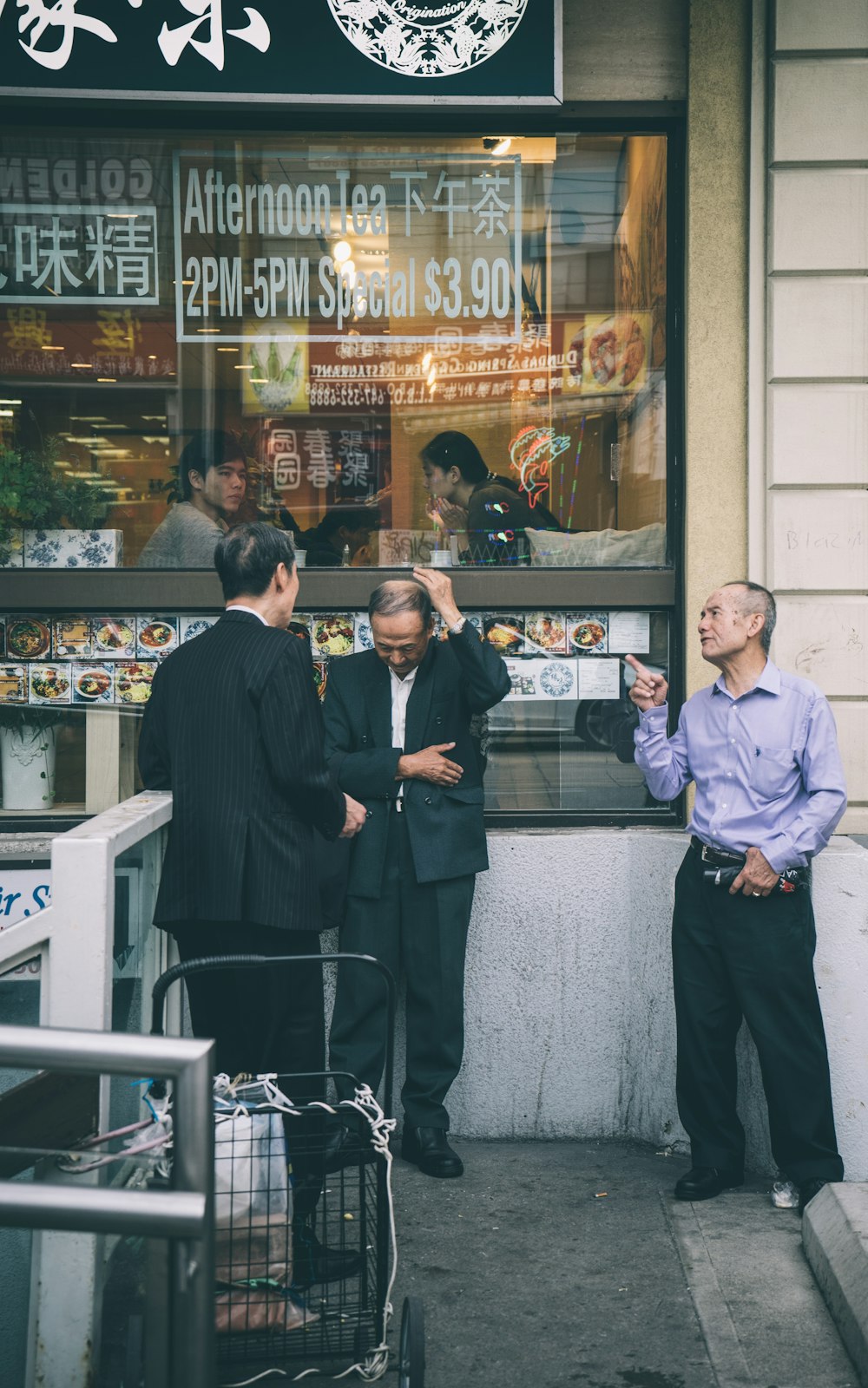 three men standing beside building