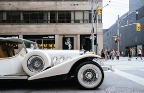 photo of classic white vehicle near pedestrian lane