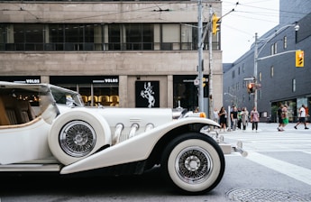photo of classic white vehicle near pedestrian lane