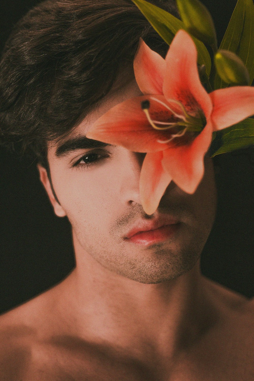uomo in topless con fiore rosa sull'orecchio