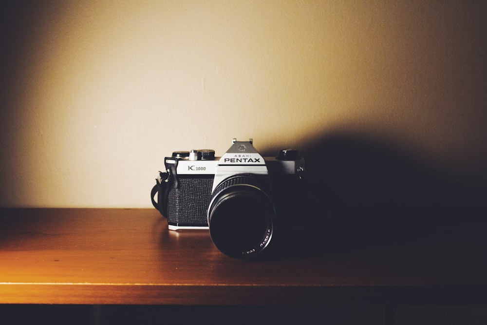 black and gray Pentax digital camera on wooden surface