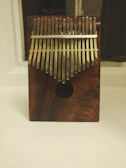 Close-up of hands gently playing a wooden kalimba under soft natural light.