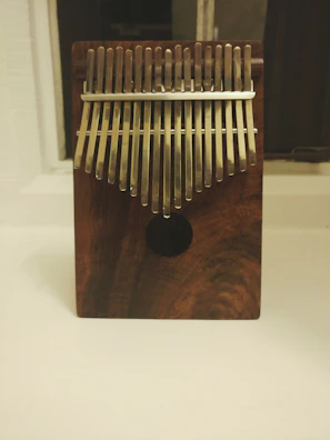 Close-up of hands gently playing a wooden kalimba under soft natural light.