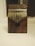 A wooden kalimba with a dark wood base and metal tines is centered against a soft, neutral background. The texture of the wood is smooth with visible grain patterns, and the metal tines are arranged in a fan-like pattern.