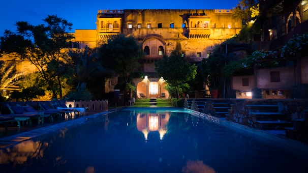 Evening shot of the resort’s illuminated facade reflecting in a tranquil water feature.