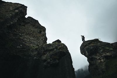 A rugged adventurer silhouetted against a stormy mountain peak under a matte-black sky.