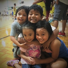 Children and coaches sharing a joyful moment on the basketball court during practice.