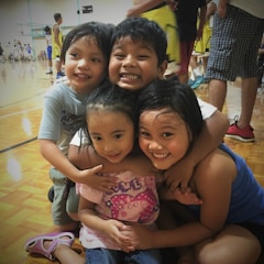Children playing basketball together, smiling and focused.