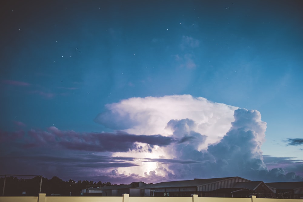 白い雲と青い空の下の灰色の家