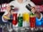 A bartender is preparing cocktails with various colorful drinks laid out in front. There are red, green, yellow, and blue drinks in distinct glasses, garnished with items like lime and mint. Ice cubes are scattered across the counter, adding to the refreshing vibe.