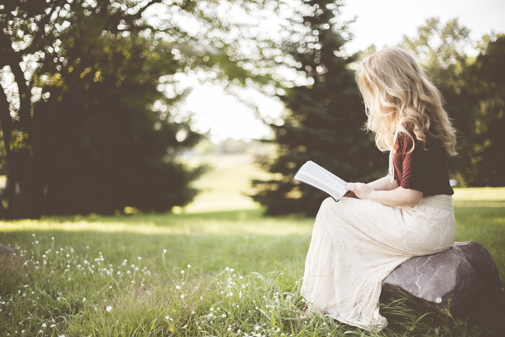 woman sitting while reading book