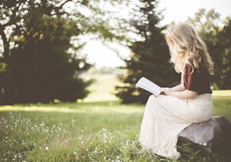 woman sitting while reading book