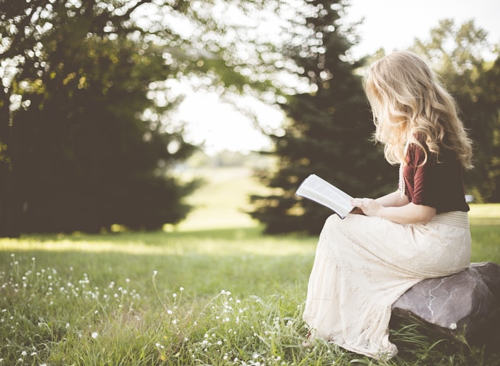 woman sitting while reading book